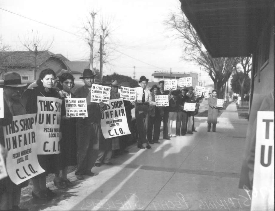 picketers holding signs along a sidewalk in opposition to anti-union shop